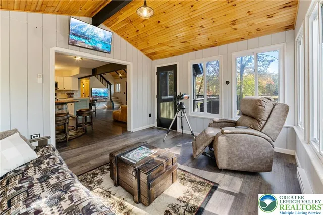 a living room with stainless steel appliances furniture a rug and a kitchen view