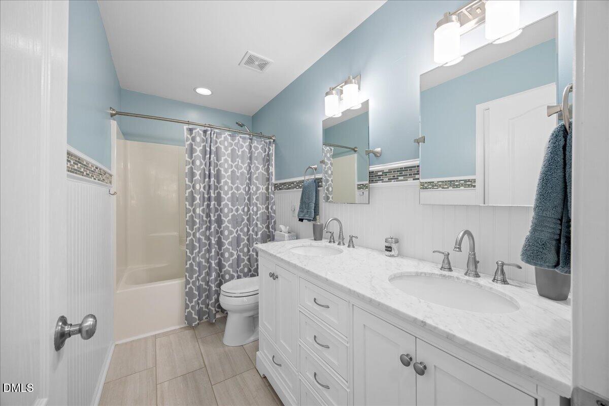 7728 Silver View Lane Raleigh, NC 27613 - Photo 30 of 53 a bathroom with a double vanity sink toilet mirror and shower