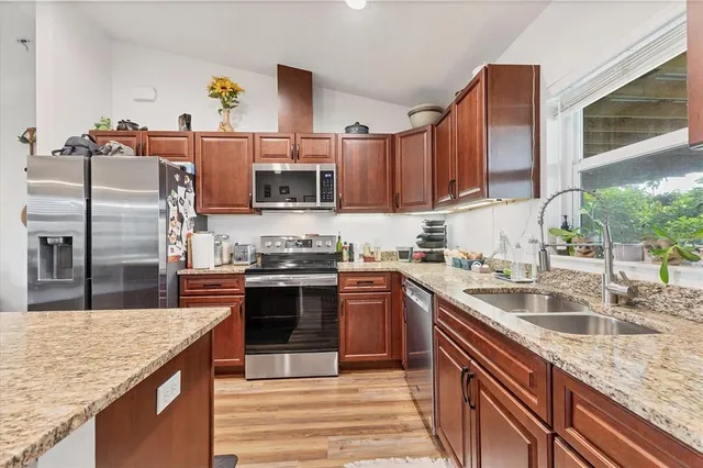 a kitchen with kitchen island granite countertop a sink counter space cabinets and stainless steel appliances