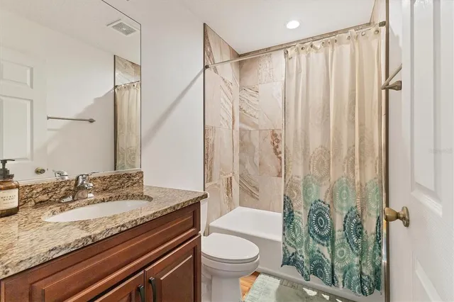 a bathroom with a granite countertop sink a toilet and a shower
