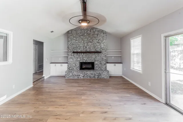 a view of an empty room with wooden floor and a mirror