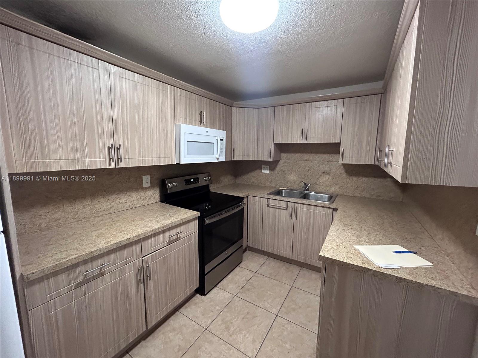 14250 Southwest 62nd Street, Unit 302 Miami, FL 33183 - Photo 2 of 8 a kitchen with a sink stove and cabinets