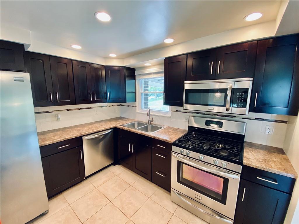 27 Flora Road Pittsburgh, PA 15227 - Photo 7 of 19 a kitchen with stainless steel appliances a stove sink microwave and cabinets