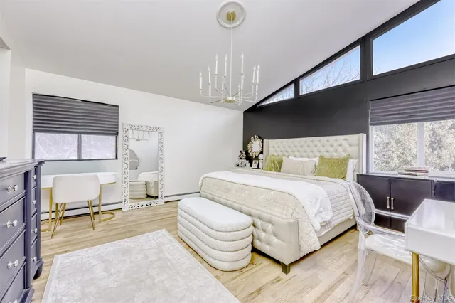 a bedroom with a bed a chair and potted plant with the wooden floor