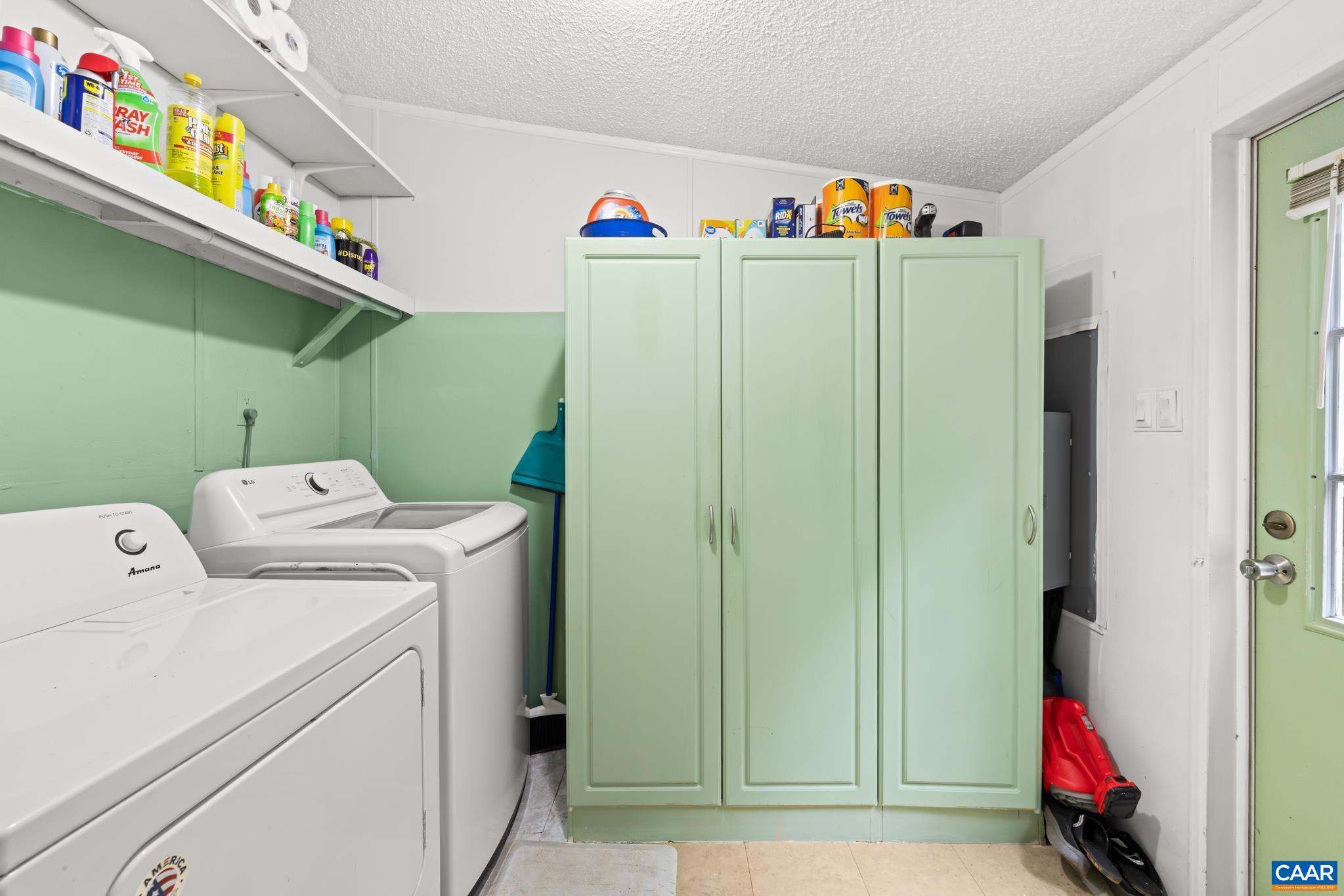 61 Snapdragon Road Ruckersville, VA 22968 - Photo 23 of 47 Functional laundry room and mudroom space featuring side-by-side appliances, overhead shelving, and stylish sage green storage cabinets! Includes a convenient exterior entry door for easy access and organized, stress-free daily routines.