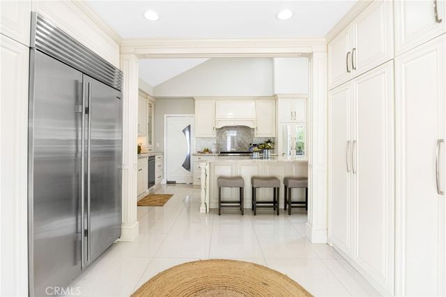 a dining hall with stainless steel appliances granite countertop a refrigerator and a sink