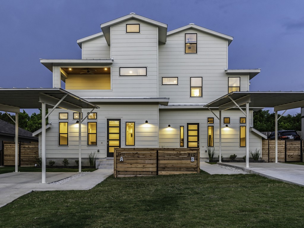 Contemporary duplex exterior featuring light-colored horizontal siding, multiple window styles, and a second-story covered balcony
