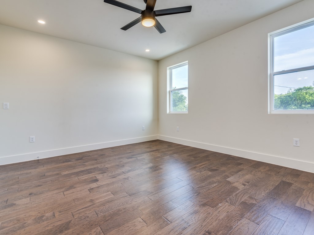 6412 Carson Ridge, Unit B Austin, TX 78741 - Photo 13 of 29 an empty room with wooden floor fan and windows