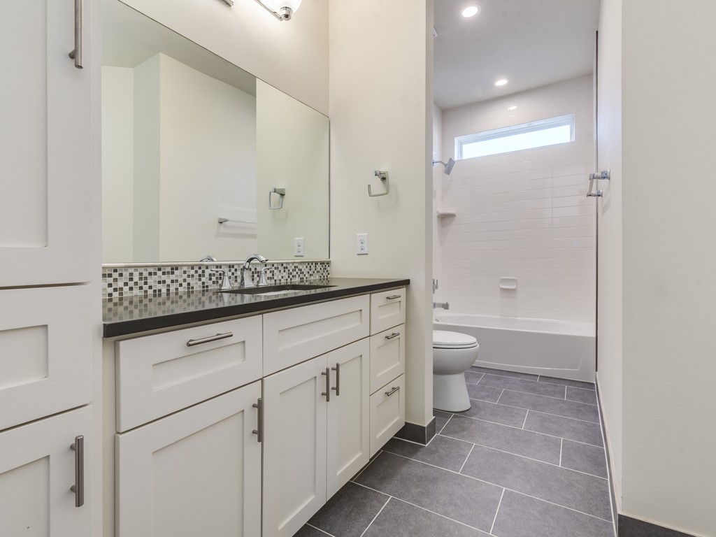 6412 Carson Ridge, Unit B Austin, TX 78741 - Photo 15 of 29 a spacious bathroom with a granite countertop sink a toilet and a bathtub