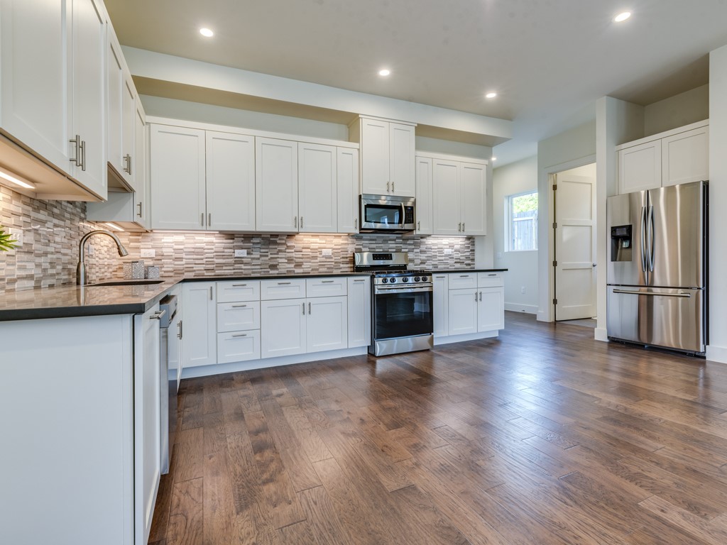 6412 Carson Ridge, Unit B Austin, TX 78741 - Photo 5 of 29 a kitchen with stainless steel appliances granite countertop a refrigerator a stove top oven a sink and dishwasher with wooden floor