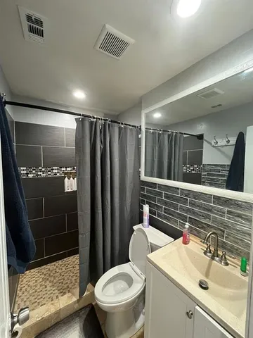 a bathroom with a sink a toilet a mirror and shower
