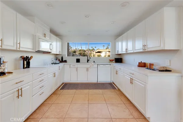 a kitchen with kitchen island granite countertop white cabinets white stainless steel appliances with a sink and dishwasher
