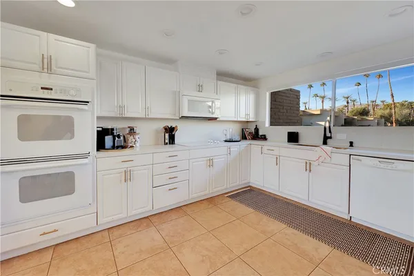 a kitchen with white cabinets and white appliances