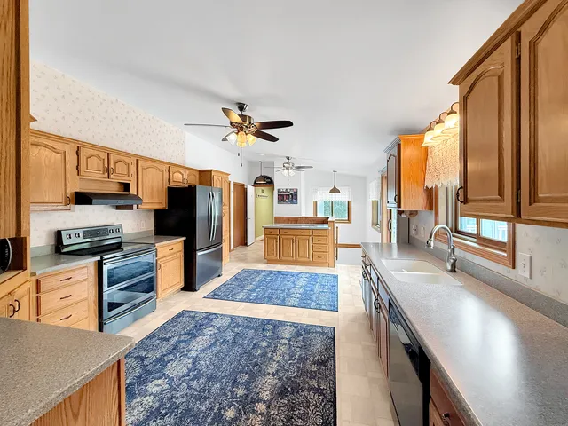 a large kitchen with stainless steel appliances a large counter top a stove and a refrigerator