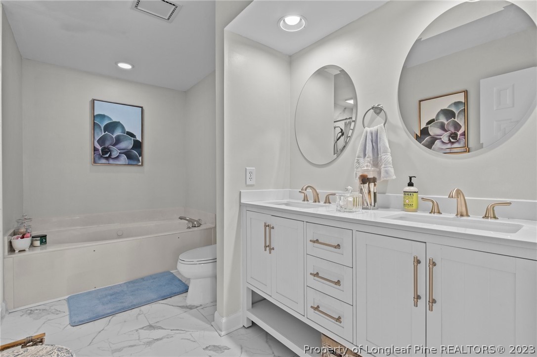 269 Knoll Road, Unit 409 Southern Pines, NC 28387 - Photo 18 of 40 a bathroom with a double vanity sink a toilet and a bathtub