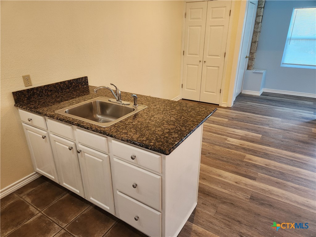 1015 Old Mill Road, Unit 4A Salado, TX 76571 - Photo 13 of 17 a kitchen with granite countertop white cabinets and a sink