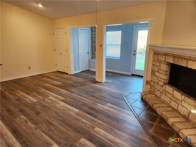a view of empty room with wooden floor and fireplace