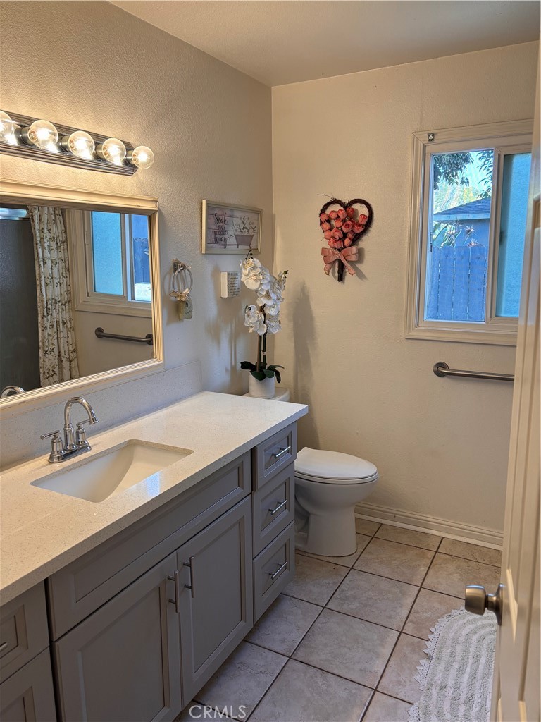 5604 Tower Road Riverside, CA 92506 - Photo 52 of 70 a bathroom with a granite countertop toilet a sink and mirror