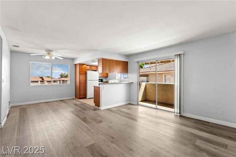 Kitchen featuring brown cabinets, freestanding refrigerator, light countertops, light wood-style floors, and a ceiling fan