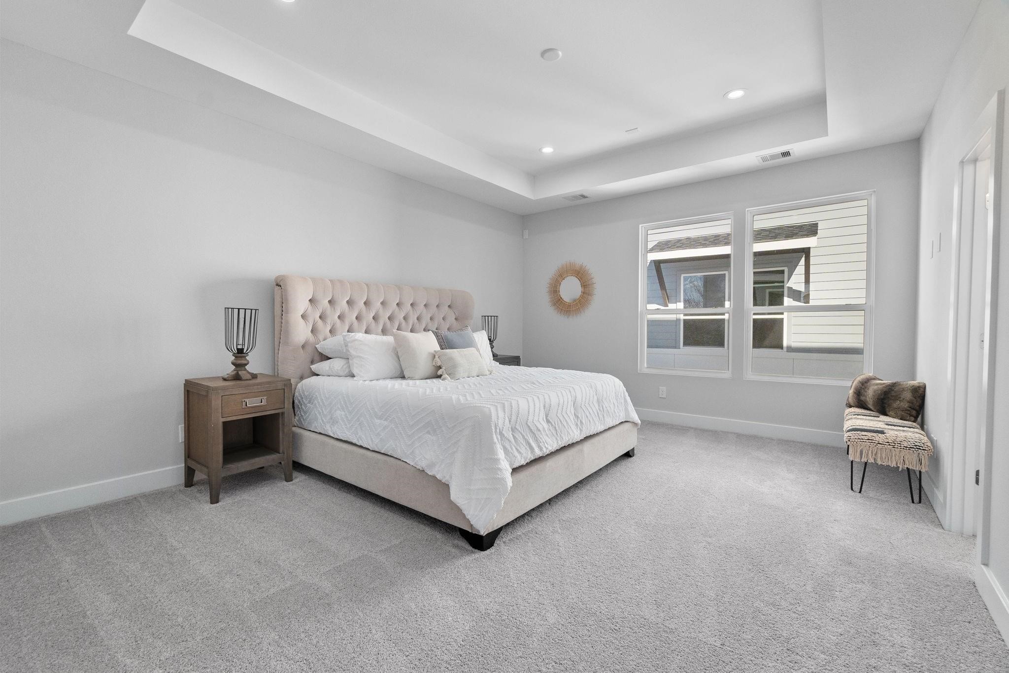 903 Quitman Street, Unit B Houston, TX 77009 - Photo 9 of 23 Expansive primary suite featuring tray ceilings, plush carpeting, and large windows that fill the space with natural light.
