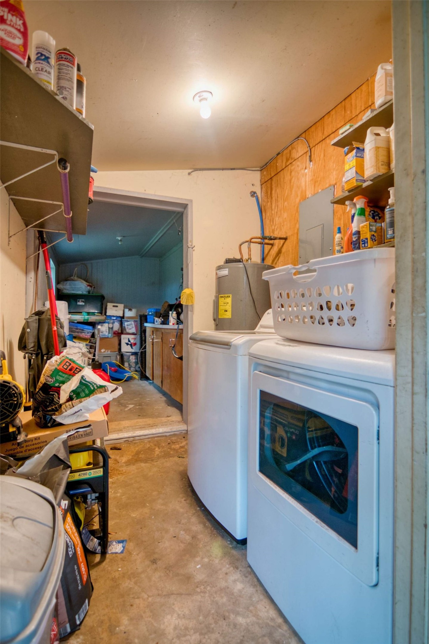 904 Bluebonnet Road Mason, TX 76856 - Photo 21 of 28 Utility area featuring a water heater, laundry appliances, and wall-mounted shelving