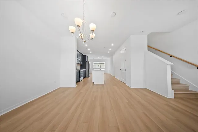 a view of a hallway with wooden floor and a chandelier
