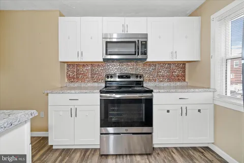 a kitchen with granite countertop white cabinets and stainless steel appliances