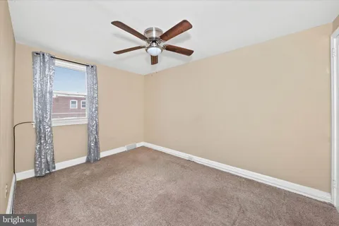 an empty room with a ceiling fan and a window