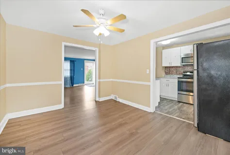 an empty room with wooden floor and a kitchen space