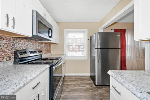 a kitchen with granite countertop a refrigerator stove and sink