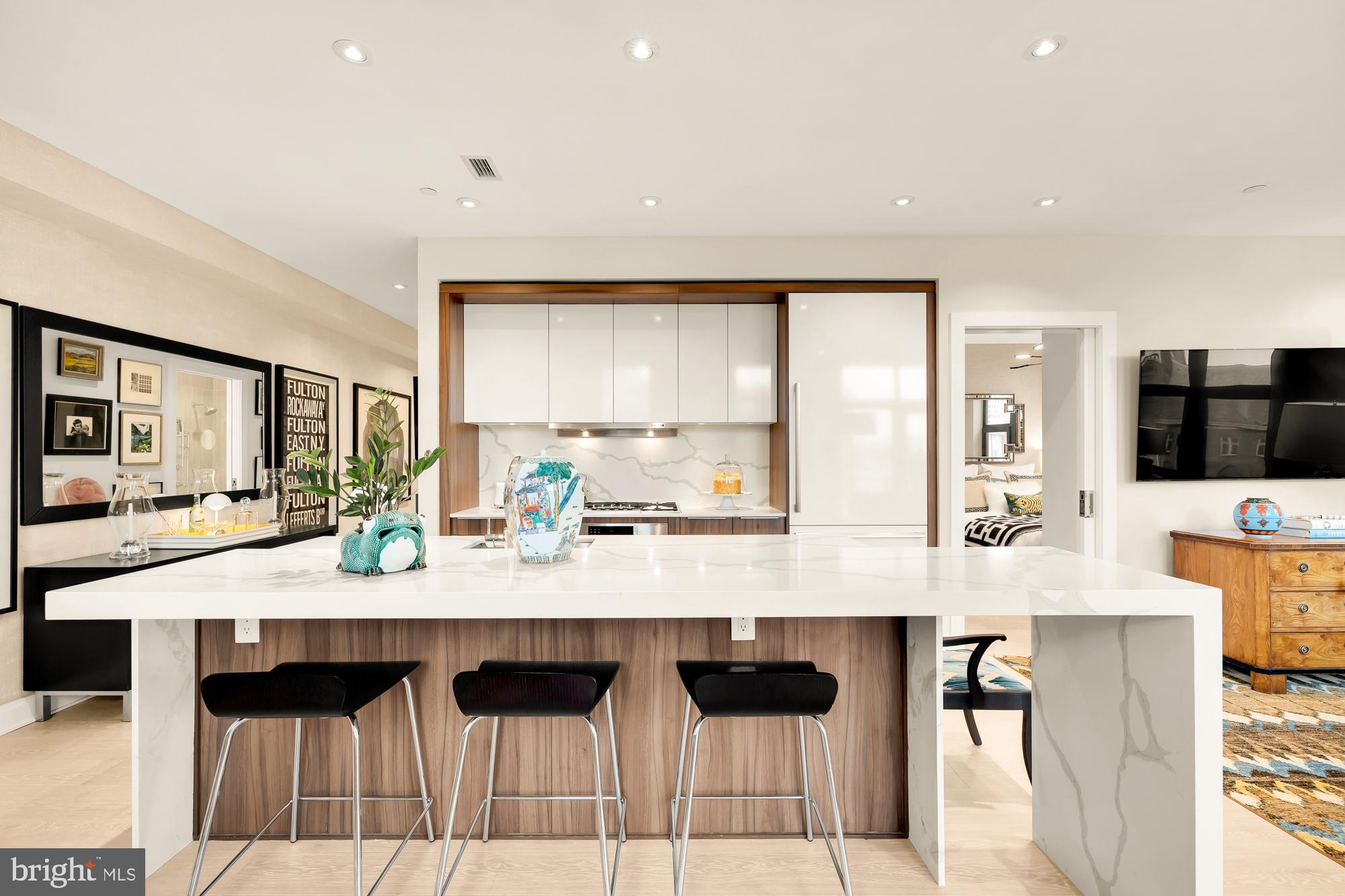 1427 Rhode Island Avenue Northwest, Unit 404 Washington, DC 20005 - Photo 11 of 35 a large white kitchen with granite countertop a table chairs sink and cabinets