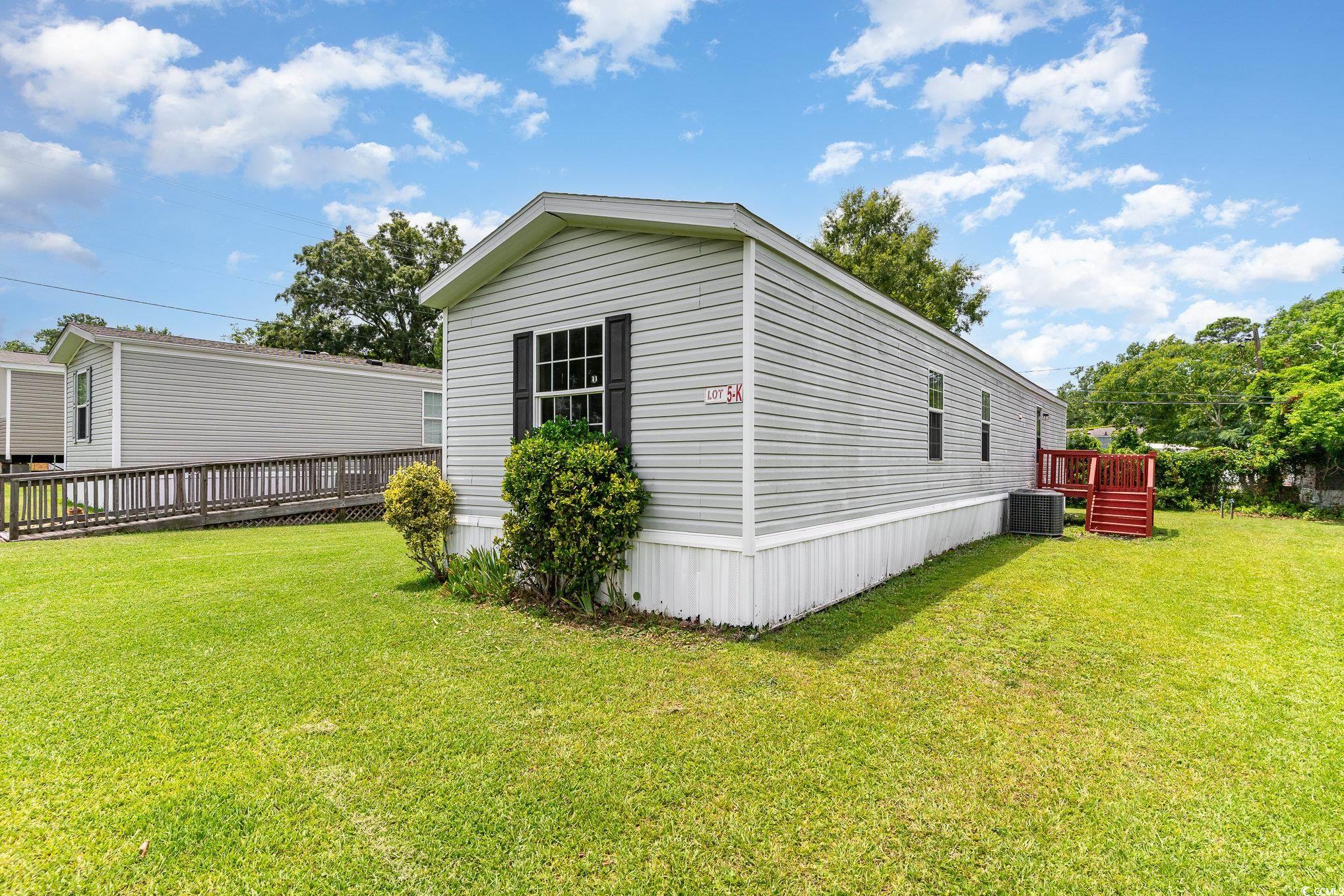 View of side of property with a lawn and central AC unit