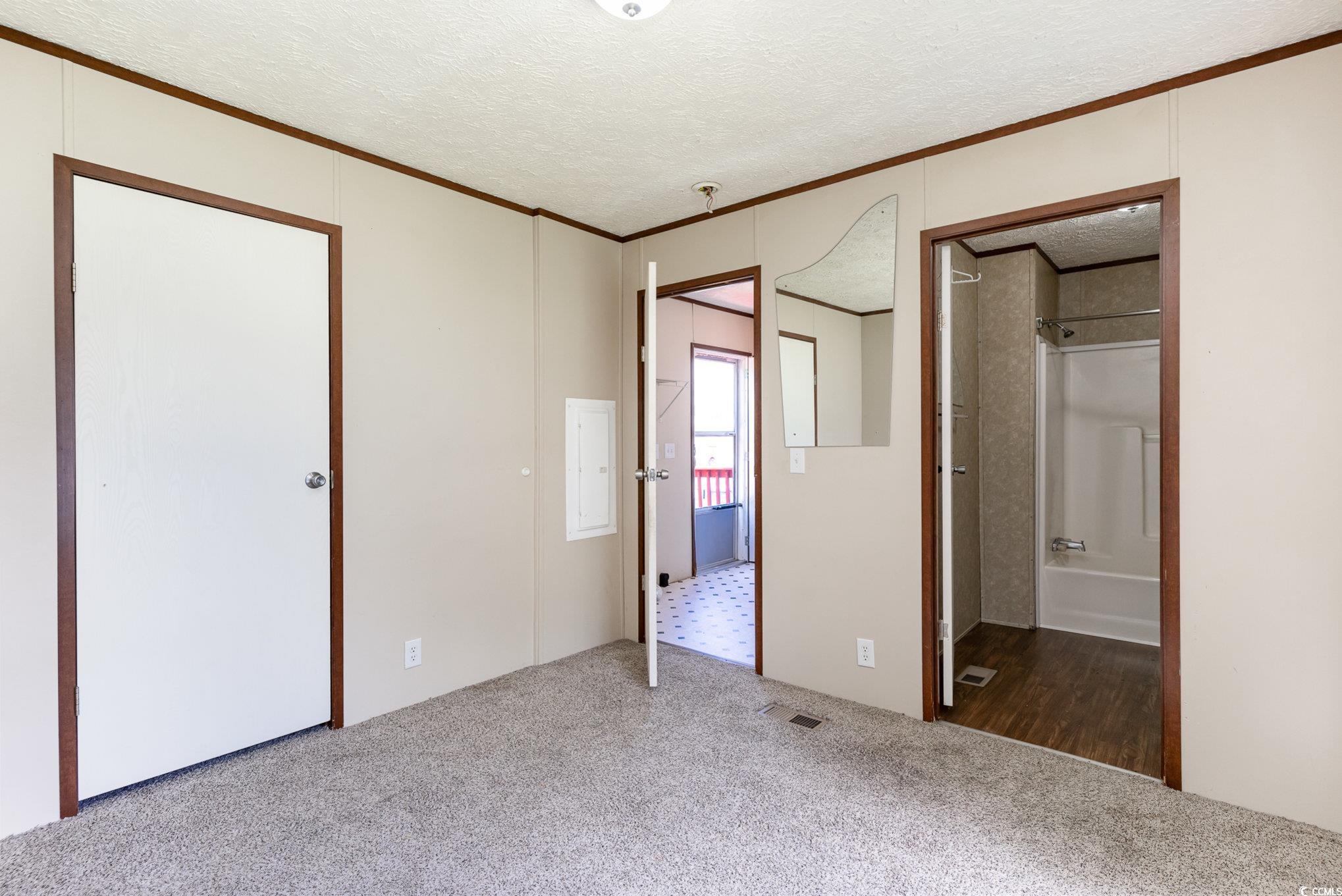 2100 Highway 15 Myrtle Beach, SC 29577 - Photo 14 of 35 Unfurnished bedroom featuring crown molding, connected bathroom, carpet, and a textured ceiling