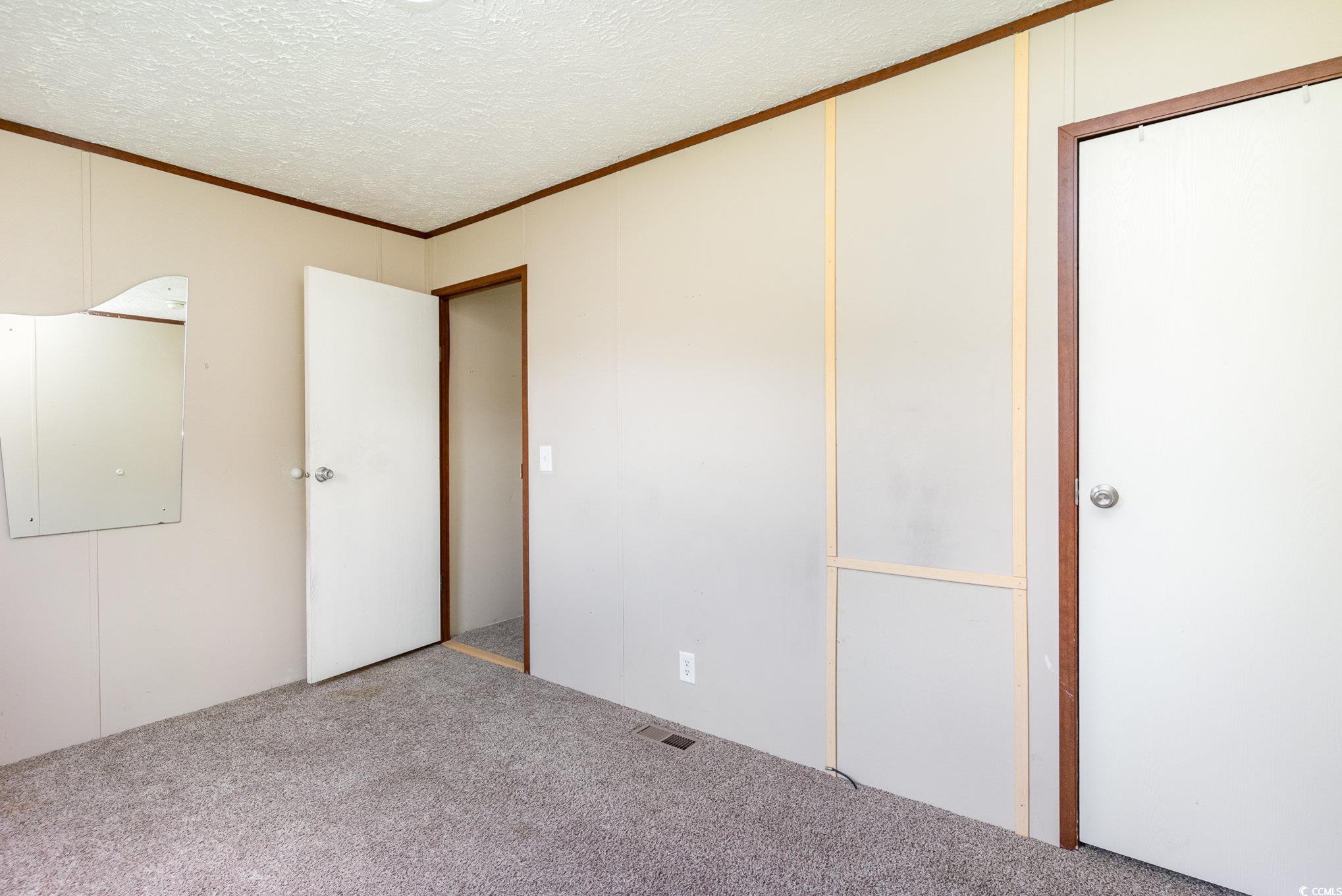 2100 Highway 15 Myrtle Beach, SC 29577 - Photo 16 of 35 Unfurnished bedroom with a closet, carpet, ornamental molding, and a textured ceiling