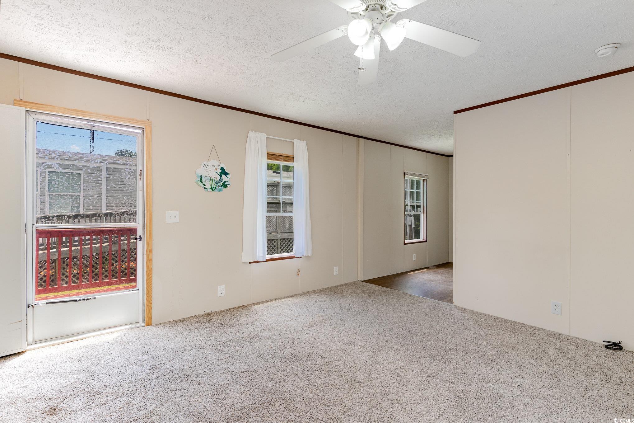 2100 Highway 15 Myrtle Beach, SC 29577 - Photo 7 of 35 Spare room with crown molding, a textured ceiling, ceiling fan, and carpet flooring