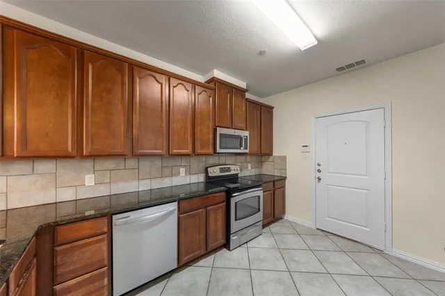 a kitchen with granite countertop stainless steel appliances a sink window and cabinets