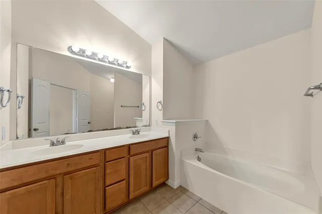 a bathroom with a tub double sink and mirror