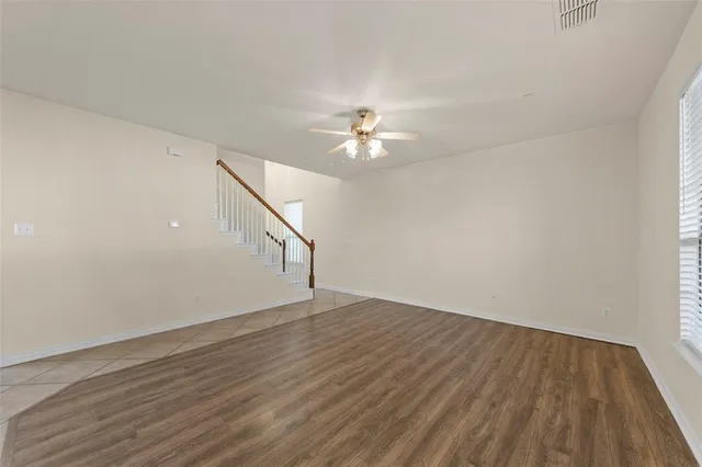 a view of empty room with wooden floor and fan