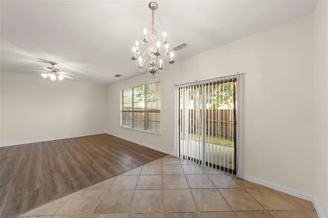 a view of an empty room with a chandelier fan and window
