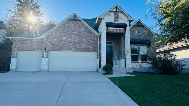 a view of a house with brick walls and a yard with a large tree