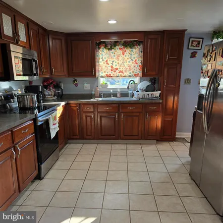 a kitchen with stainless steel appliances granite countertop a stove top oven a sink a counter space and cabinets