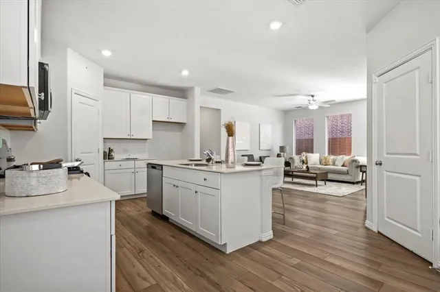 a kitchen with counter top space a sink wooden floor and view living room