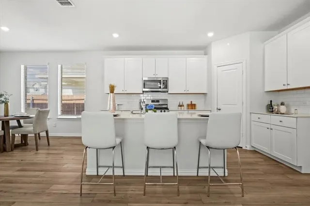 a white kitchen with wooden floors and white stainless steel appliances
