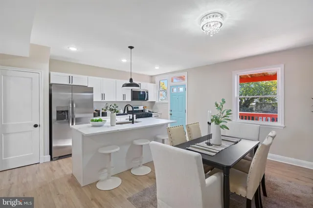 a kitchen with stainless steel appliances a dining table chairs and refrigerator