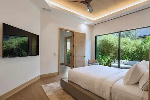 a bedroom with a large bed and a flat tv screen on dresser