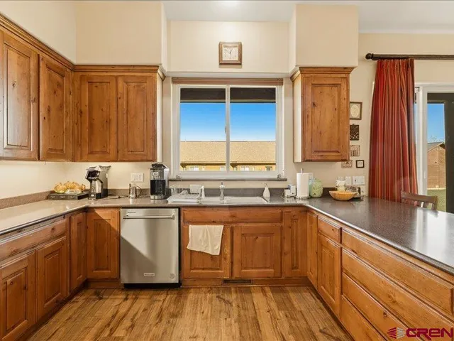 a kitchen with stainless steel appliances granite countertop wooden cabinets a sink and dishwasher a stove with wooden floor