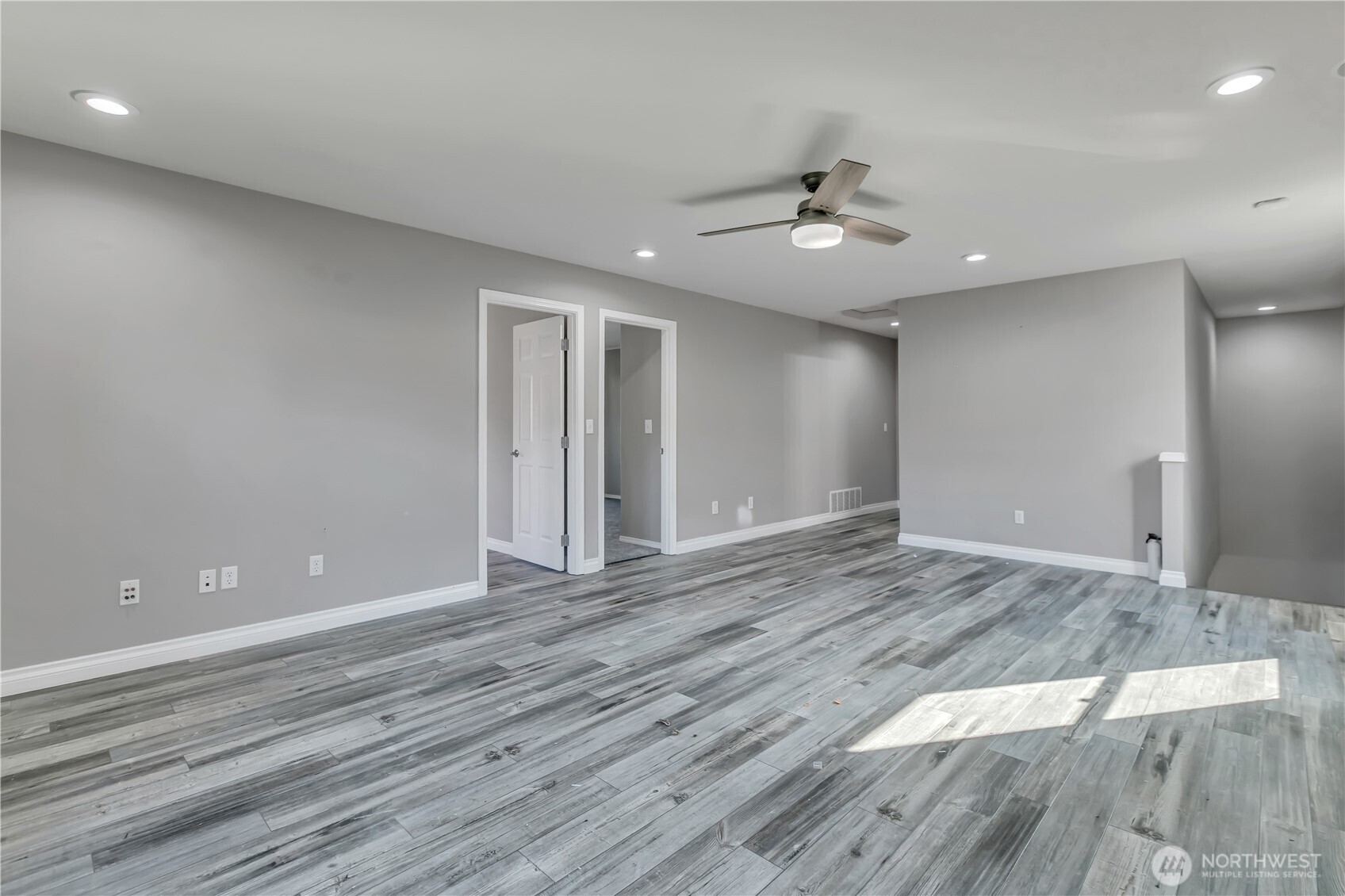 23516 Southeast 243rd Place Maple Valley, WA 98038 - Photo 19 of 33 a view of an empty room with wooden floor and a ceiling fan