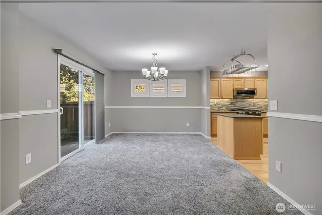 an empty room with chandelier fan and windows