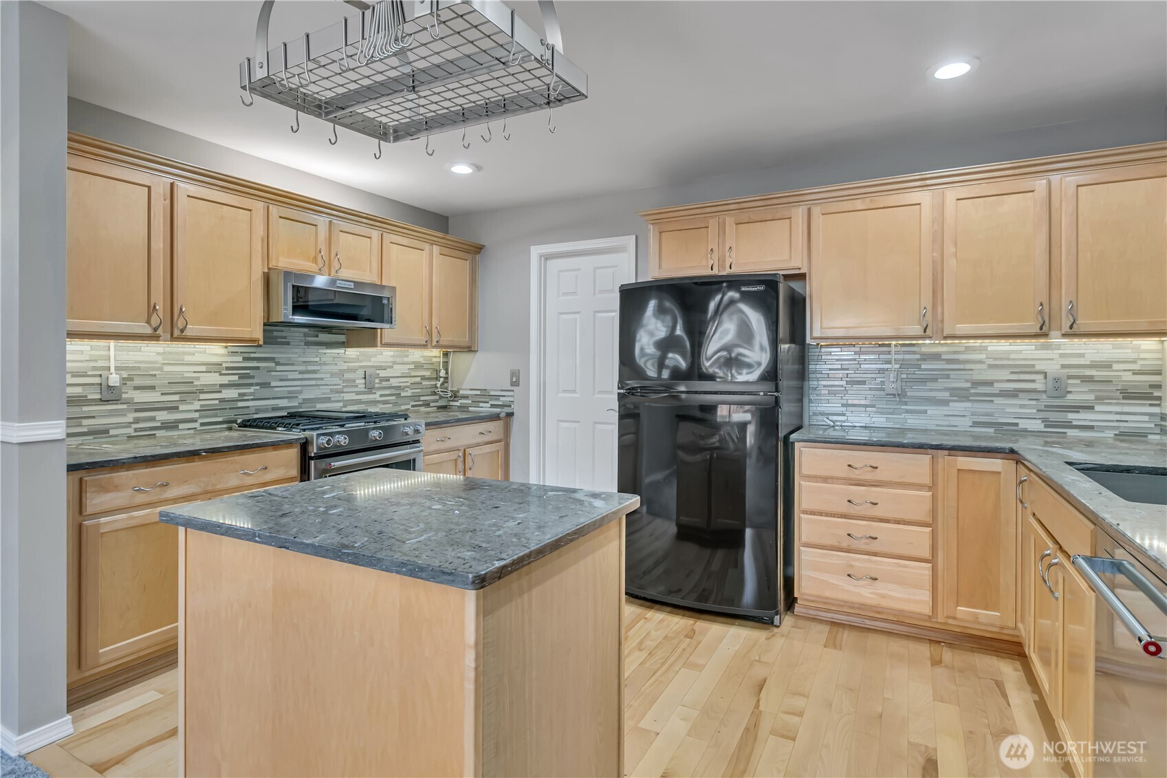 23516 Southeast 243rd Place Maple Valley, WA 98038 - Photo 9 of 31 a kitchen with kitchen island granite countertop a stove top oven a sink dishwasher and a refrigerator with wooden cabinets