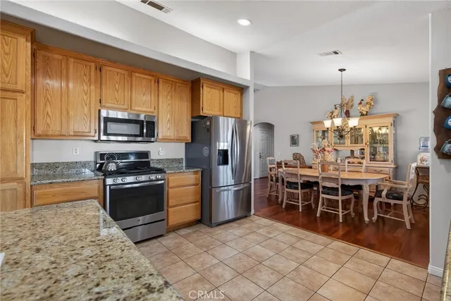 a kitchen with stainless steel appliances granite countertop a stove refrigerator a microwave oven with a dining table and chairs